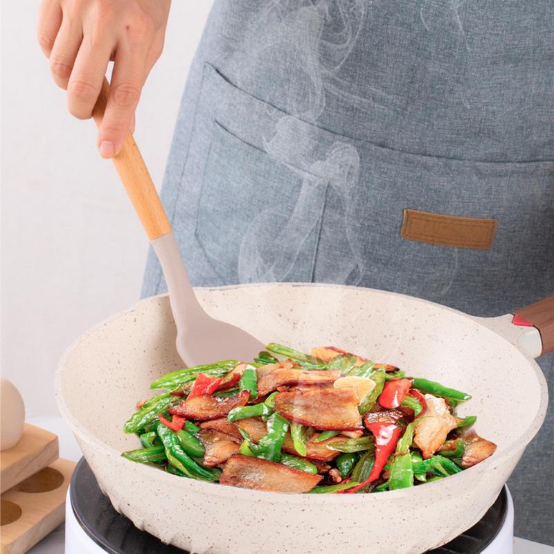 Using a spatula from the pink Silicone Kitchen Utensils Set to toss a vegetable and meat stir fry