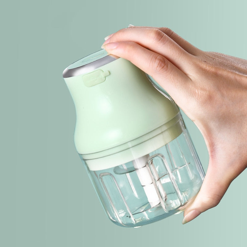 Green Mini Electric Food Chopper being held by someone showing its the size of your hand and easily held