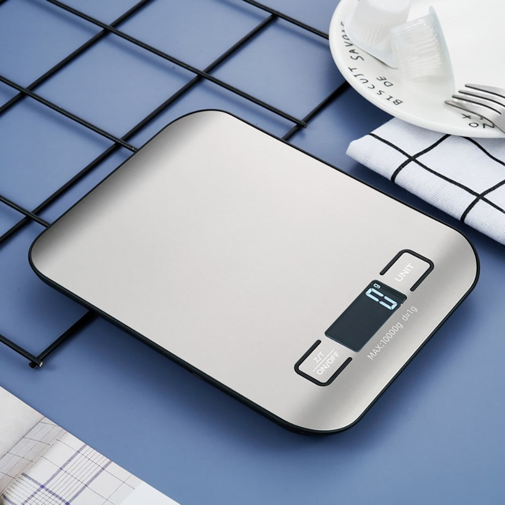 The electronic kitchen scale placed on a bench next to the tea towl, plate and fork