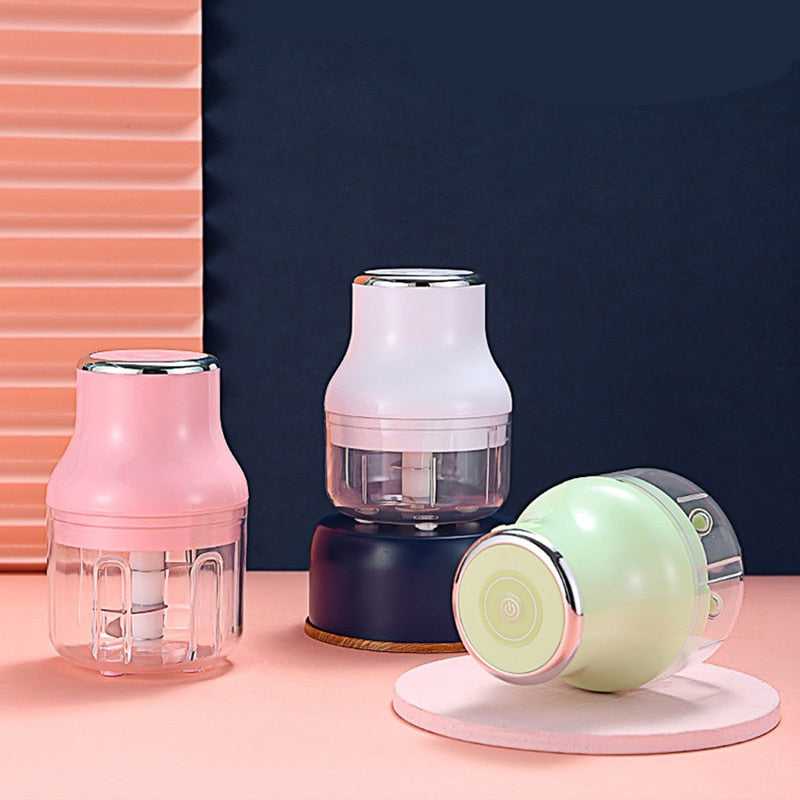 A Pink, Blue and Green Mini Electric Food Chopper aligned next to each other. The Green one is on its side