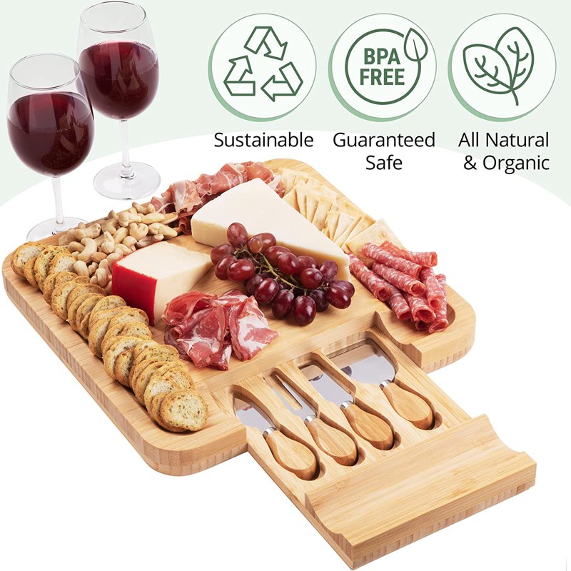 Sustainable, Guaranteed safe, All natural and organic. Bamboo Cheese Board & Knives Set set up containing a variety of antipasto foods accompanied by 2 glasses of wine